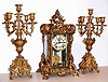 Ansonia Clock Co., New York, "Apex" crystal regulator three piece garniture set with matching candelabra 8 day, time and gong strike spring driven movement in gilded brass case with four beveled glasses and Roman numeral cream enamel dial, c1905