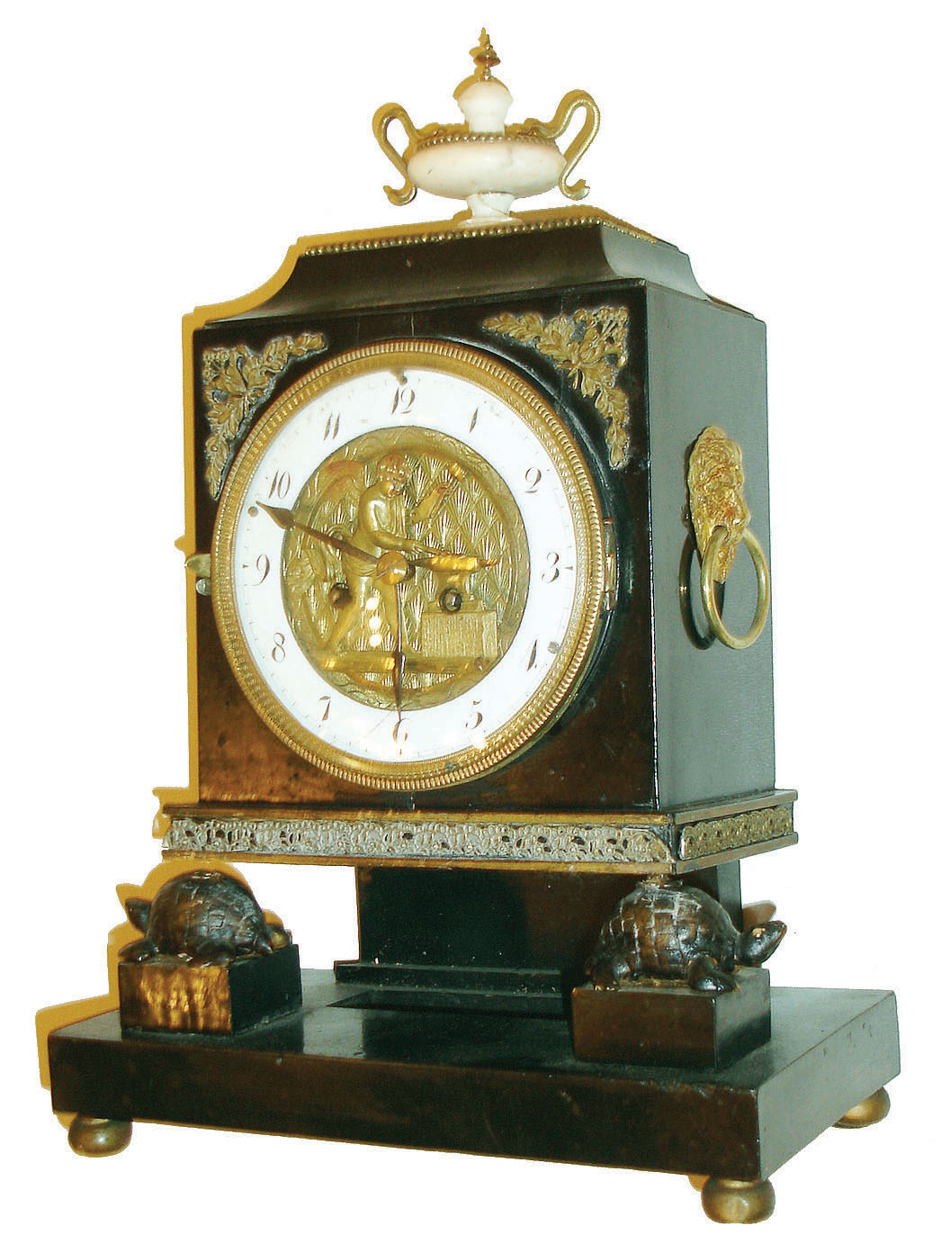 Austria, mantel clock with automata on dial, the ebonized case supported at the front corners by gilt turtles, front with stamped brass ornament, case sides with lion mask handles, top with alabaster urn mounted with snake form handles, beaded brass trim , and brass finial, Arabic numeral, white enamel dial with an automated figure representing Cupid forging arrows, the figure striking his anvil as the clock sounds, blued steel hands, two day time and strike movement, fancy brass pendulum with silk suspension, c1830 — Antique Clocks Price Guide