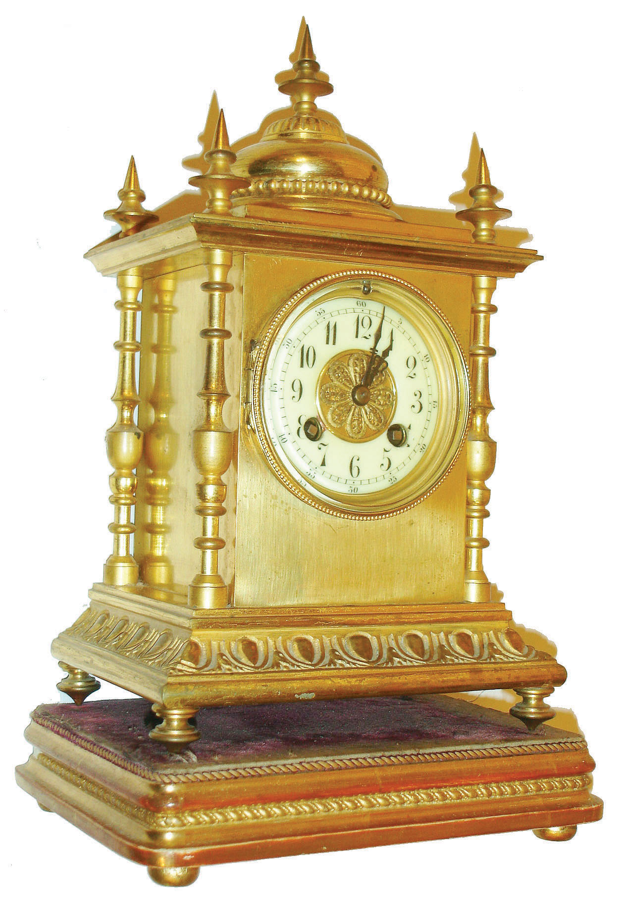 France, gilt brass mantel clock, on turned feet, deep cavetto base with modified egg and dart design, the four corners with ornately turned columns, the top with 5 finials and squat dome with bead molding, gilt bezel with beveled glass, Arabic numeral white enamel dial, blued steel hands, 8 day time and strike pendule a Paris movement signed S. Marti, striking on a gong, all on a gilt, molded wooden base on compressed ball feet, c1900 — Antique Clocks Price Guide