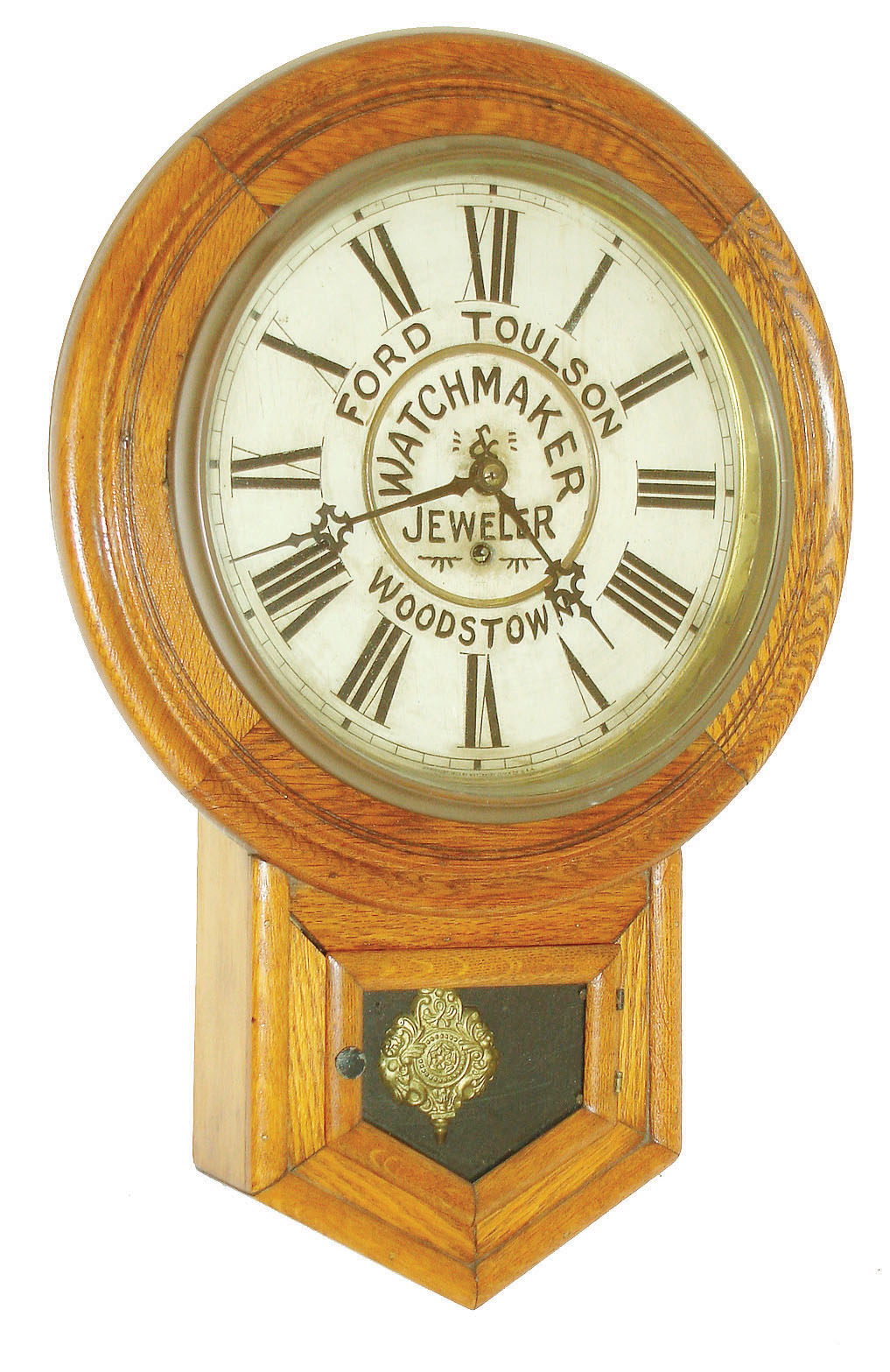 Waterbury Clock Co., Waterbury, Conn., short drop wall clock, 8 days, time only, spring driven movement in an oak case with advertising on painted metal dial "FORD TOULSON WATCHMAKER & JEWELER WOODSTOWN,", c1900 — Antique Clocks Price Guide