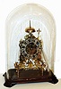English, 2-fusee skeleton clock, striking full hours on a gong behind and half hours on bell, frame signed Smith and Sons on a small silvered brass plaque near bottom, the whole on a wooden base, c1875