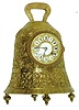 France, brass bell form table clock, the casting with foliate designs and human figures playing various musical instruments, and Latin phrases with religious significance, top with handle, and base with gadrooned feet, cast bezel with pendant husks and convex beveled glass, brass dial with applied white enamel cartouches with Roman numerals, blued steel hands, 8 day time and strike pendule a Paris movement, striking on a gong, c1890