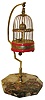 Toyo Clock Factory, Japan, bird cage clock, brass cage on red striped base with brass feet, rotating globe with pointer indicates time, bird attached to end of pallet arbor moves back and forth as clock ticks, the cage suspended from a polished metal hanger mounted to an octagonal marble base, c1930