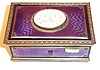 German, Singing Bird Box, key wound, actuated at will with slide on right front of case, the bird singing for his audience and then disappearing from view, from Karl Griesbaum factory, in a light violet guilloche enameled case with a carved ivorene cover over the bird and four ivorene feet, & slide with 4 tiny roses, late 20th century.