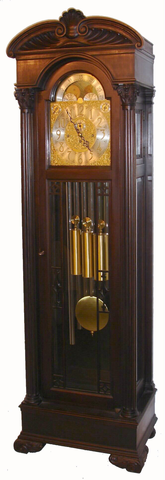 Colonial Mfg. Co., Zeeland, Michigan, Model No. 1211, 9-tube hall clock, 8 day, time, strike and chime, three weight driven European movement playing Whittington, Westminster or Canterbury tune in maple case stained dark walnut with ornately carved full length Corinthian columns, well carved bracket feet and crest, beveled glass sides and locking beveled glass side doors accessing movement. The brass arched dial has a silvered chapter ring with applied brass numerals, cast spandrels and dial center, rolling moon phases  in arch, selection for tunes or silent, and second's bit, c1930 — Antique Clocks Price Guide