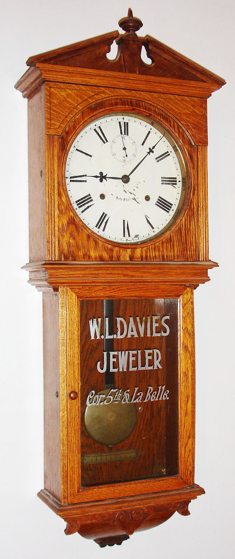 Seth Thomas Clock Co., Thomaston, Conn., "Umbria" wall clock, 15 day, time only, double spring driven movement in an oak case with painted metal dial and advertising tablet for "W.L. DAVIES JEWELER Cor. 5th and LaBelle" on lower door, c1894 — Antique Clocks Price Guide
