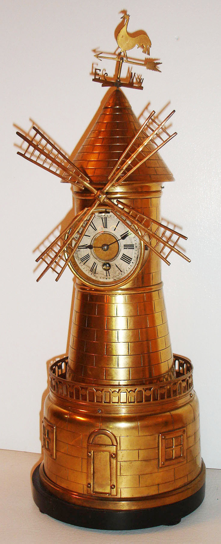 French Industrial, windmill, the polished brass case with black marble base, mid section with pierced gallery, topped with a weathervane, lower section with two simulated windows flanking a door, which slides up to allow separate windmill movement to be wound, with eight day time only movement with cylinder platform, silvered Roman numeral dial with gilt center, and blued steel spade hands, c1870 — Antique Clocks Price Guide