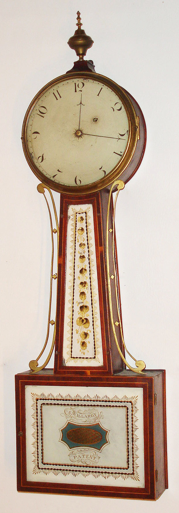 Boston area banjo wall clock, 8 day, time only, weight driven T-bridge movement in a mahogany case with string inlay and reverse painted tablets in throat and lower door and painted metal dial and barb hands, c1805 — Antique Clocks Price Guide