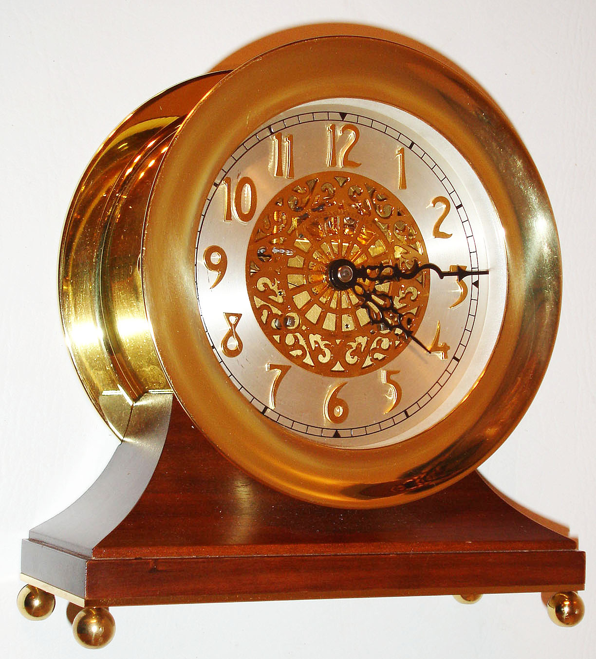 Chelsea Clock Co., Boston, Mass., "Centennial Edition" ships bell clock, eight day time and ships bell strike movement with platform lever escapement, silvered dial with pierced gilt center and applied gilt Arabic numerals, black painted steel hands, polished brass case with hinged bezel, mounted to a walnut base supported by polished brass ball feet, No. 0031, c1997 — Antique Clocks Price Guide