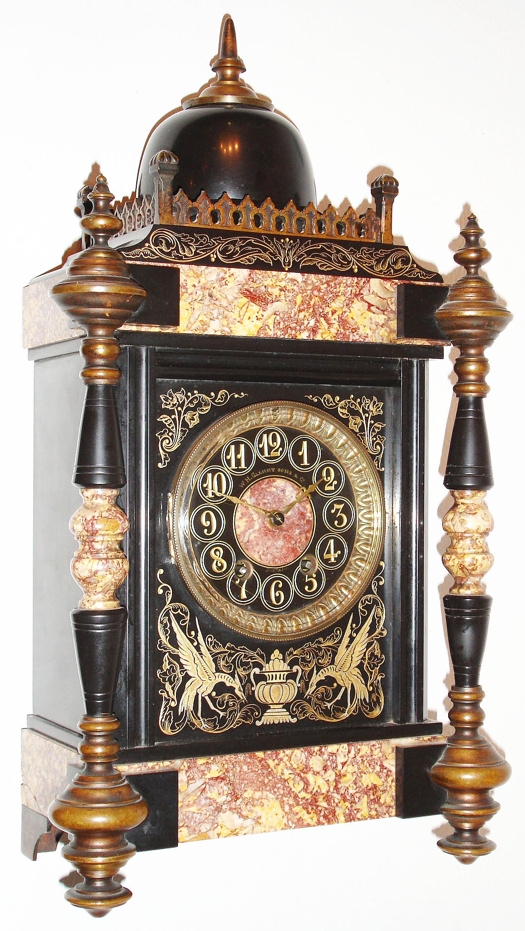 France, Belgian slate and multi colored marble mantel clock, the front with incised gilt and silvered ornament depicting two Phoenix eating snakes flanking a central urn, with trailing leaves, vines, and flowers, the front corners with turned slate and marble columns with gilt bronze finials and feet, the case top with Gothic inspired gilt bronze surround and slate dome, with bronze finial, black slate dial with incised gilt Arabic numerals, colored marble center, marked "W. H. Glenny and Sons and Co. Buffalo" with gilt hands, French, 8 day, time and strike, movement with square plates, c1885 — Antique Clocks Price Guide