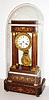 French portico clock with base and dome, 8 day, time and strike, pendule a Paris movement, recoil escapement and count wheel striking on a bell, white enamel Roman numeral dial, with unusual dedication in enamel, "For Vito Viti", fancy gilt hands, gilt brass gridiron style pendulum ornamented with dolphins, flowers and foliage, Brazilian rosewood veneered case with marquetry, the base also with rosewood veneer and light wood marquetry, with gilt bronze bezel, column capitals and bases, white painted moldings and feet, under a glass dome, c1840