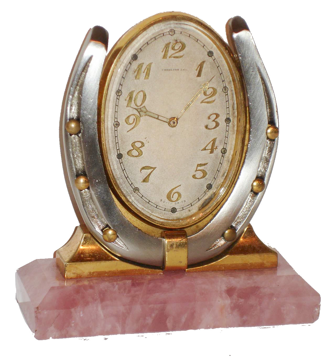 Desk or nightstand clock, polished rose quartz base supporting a silvered horseshoe with gilt nails, and an oval framed, silvered dial clock with gilt Arabic numerals, the dial signed "Charlton & Co. 8 days, Swiss" with gilt, luminous hands, nickel 15 jewel movement signed "Concord Watch Co", c1920 — Antique Clocks Price Guide