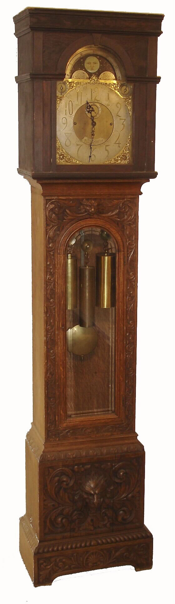 English tall clock presented "THE ASSOCIATION OF DIAMOND MERCHANTS, JEWELERS & SILVERSMITHS, 6 GRAND HOTEL BUILDINGS, TRAFALGAR SQUARE, LONDON", 8 days, time and Whittington chime on 8 bells or your choice of Westminster on 4 large flat wire gongs, and striking the hours on a still larger deep toned gong.  Brass three weight driven movement in an a heavily carved English oak case. The brass dial has silvered chapter ring, tune and silent selection dials, moon phase and brass corner spandrels, c1890 — Antique Clocks Price Guide