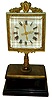 Jean Eugene Robert Houdin, Paris, fifth series mystery clock, ebonized rectangular ogee molded wooden base topped with a gilt brass platform, the center with short column supporting the square beveled glass dial with pierced brass hands, enclosed in an ornate, cast gilt frame with cartouche and floral garlands at top, 8 days, time only movement with platform escapement hidden in wooden base, and with gilt brass bottom cover, c1860