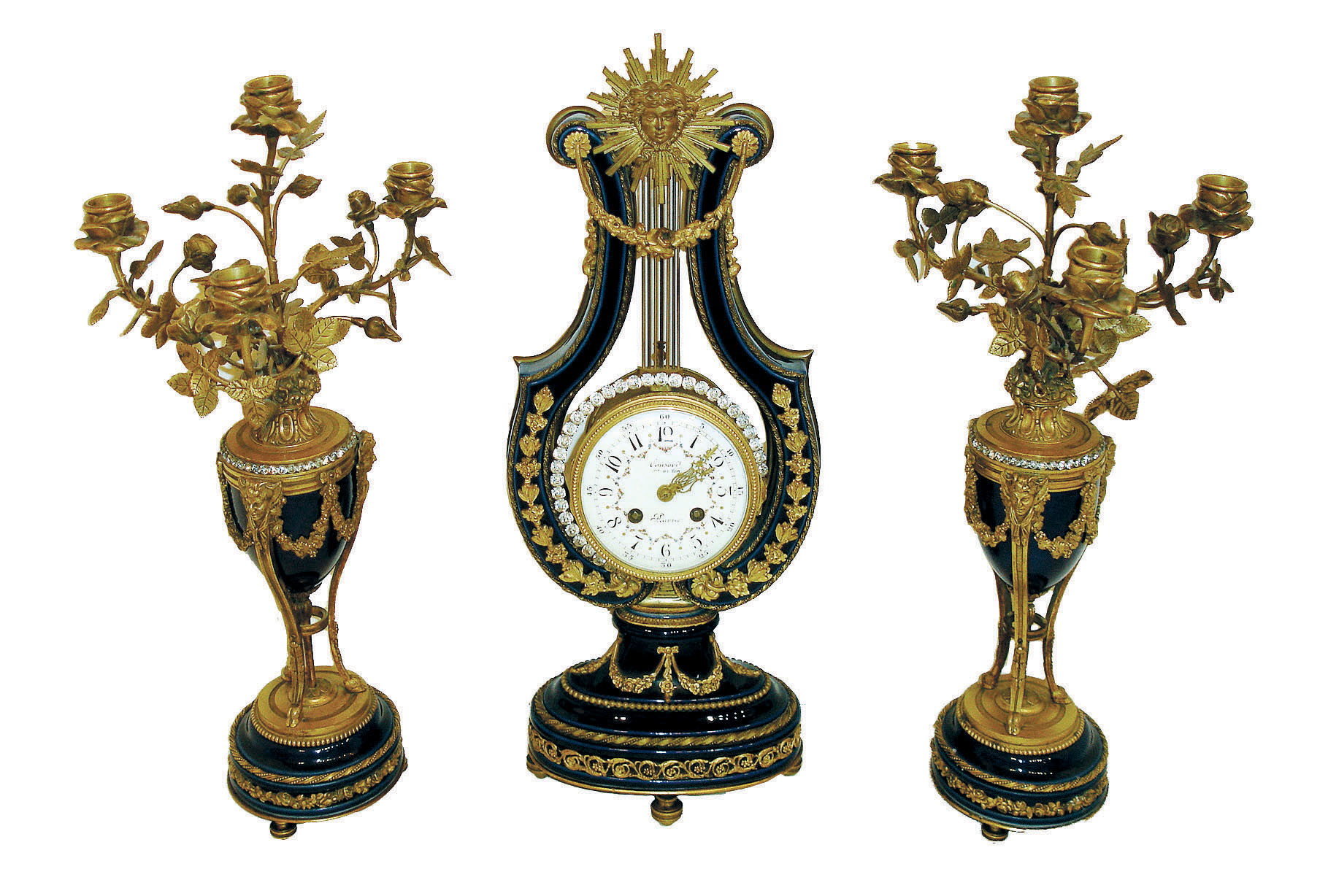 Causard, a Paris, stunning 3 piece blue cobalt porcelain and gilt bronze lyre form clock with candle stands.  The case replete with ornaments in the classical taste, the top with mask of Helios above floral festoon, the pendulum composed of a ring of brilliants with gridiron style rod, and with knife edge suspension above the movement canister and oscillating in full view, gilt bezel with convex beveled glass, Arabic numeral white enamel dial with floral garlands, signed "Causard Hger Du Roy A Paris", gilt lyre form hands, 8 days, time and strike, pendule a Paris movement, signed S. Marti, the candelabras also in cobalt glaze, set with brilliants, and with gilt classical ornament, the candle arms with rose leaves and buds, the sockets of open rose form, c1890 — Antique Clocks Price Guide