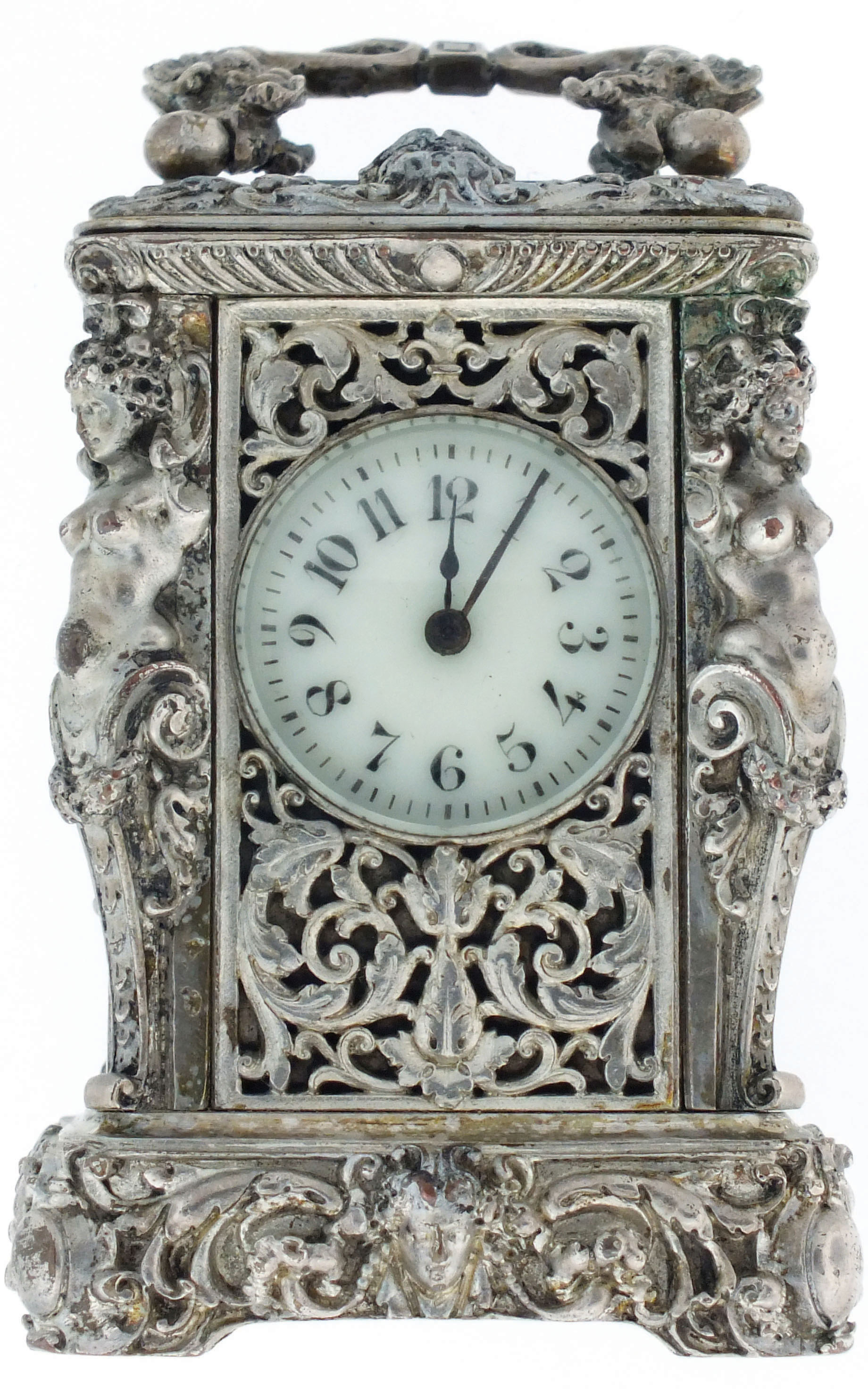 France, miniature carriage timepiece, the ornate silvered case with caryatid corners, masks, symmetrical foliate ornament and dolphin form carrying handle, top with thick beveled glass for viewing the escapement, Arabic numeral white enamel dial, blued steel spade and poker hands, 8 day time only, movement with lever platform, c1880 — Antique Clocks Price Guide