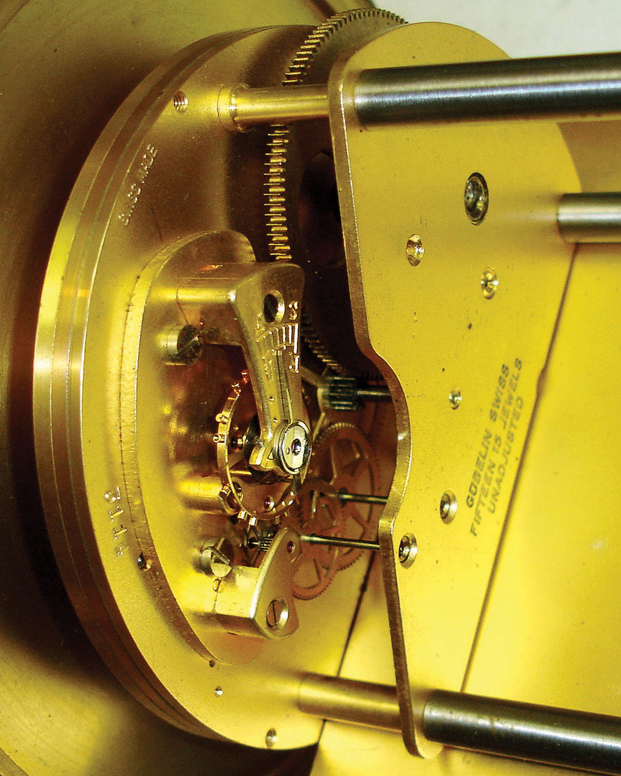 Gubelin, Switzerland, inclined plane clock, time only, gravity powered 15 jewel gilt movement with platform escapement also showing the date, silvered dial with applied gilt Roman numerals and blued steel day pointer, blued steel hands, contained in a gilt drum style case, the incline of scrolled iron with applied gilt acanthus leaf ornament, the front with engraved days of the week, all resting on gilt ball feet, c1980 — Antique Clocks Price Guide