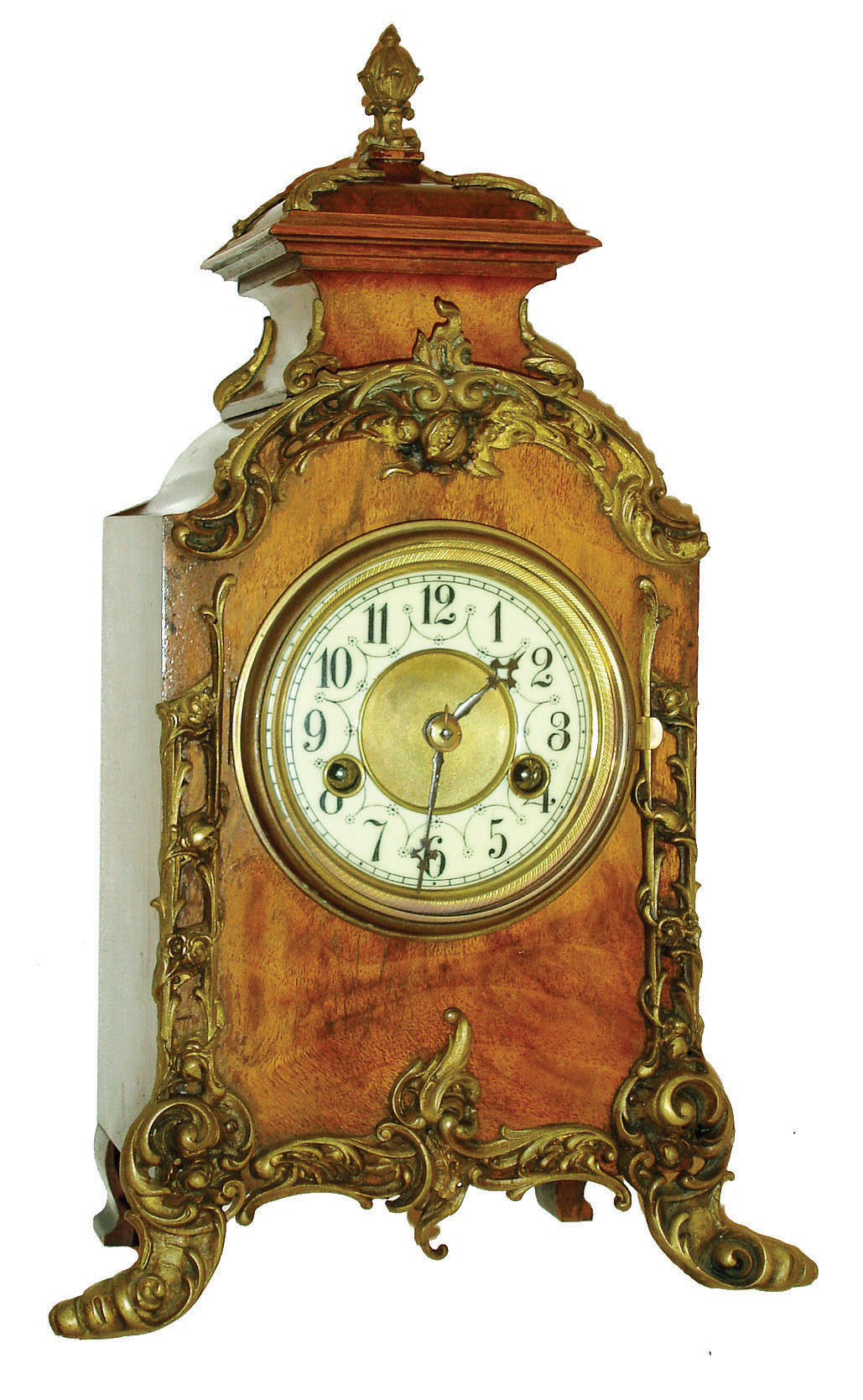 Hamburg American Clock Co., Germany, 8 days, time and strike, shelf clock in walnut veneered wooden case in the French style with applied cast foliate ornament, case top with small cast finial, brass bezel with beveled glass, Arabic numeral white enamel dial, blued steel hands, dated 1899 on label. — Antique Clocks Price Guide