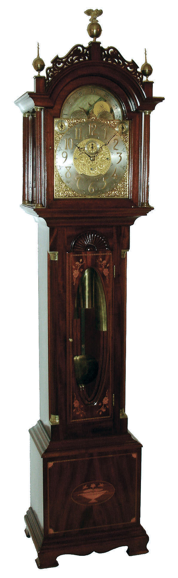 John Elliott, London, England for Bigelow, Kennard & Co., Boston, Mass., tall clock, time, strike and Westminster chime on cathedral gongs,  8 days, three brass weight driven movement in a mahogany inlaid case with floral motif on door and urn with flowers on base, both framed with herring bone inlay, Roxbury fretwork and brass capped full Corinthian columns on hood, three upper brass finials including center eagle finial, trunk door surmounted by clamshell carving and flanked by fluted quarter columns with brass caps and bases, all resting on a cutout skirt with ogee bracket feet.  The brass dial has ornately cutout and engraved brass corner spandrels and profusely engraved dial center silvered chapter ring with applied brass numerals, hour strike / silent and Westminster chime / silent selectors and moon phase dial, c1910 — Antique Clocks Price Guide