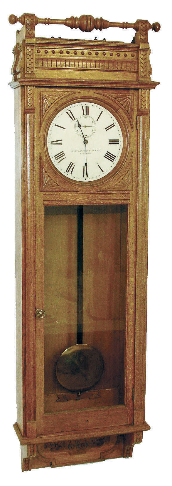 Self Winding Clock Co., New York, "Regulator No. 13" wall clock, time only, electric wound movement with meter long pendulum in an oak carved oak with fan carvings and spindle top and painted metal dial, c1887 — Antique Clocks Price Guide