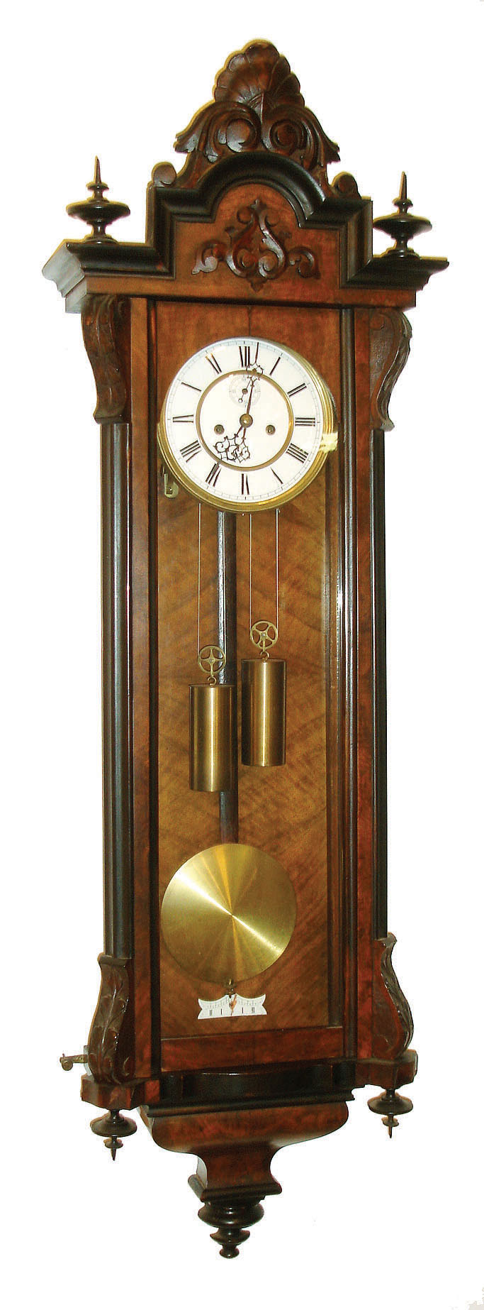Gustav Becker, Freiburg, Germany, Vienna regulator, walnut veneered case with ebonized moldings and finials, and leaf carved corbels at the top and bottom of the door, stepped top also with a removable carved crest, Roman numeral white enamel dial with small seconds below 12:00, pierced blued steel hands, brass 8 day weight driven time and strike movement, brass weights, c1880 — Antique Clocks Price Guide