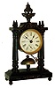 Clocks- 2 (Two): Ansonia Clock Co., New York, N.Y.: "Little Dorrit" 30 hour time and alarm black enameled metal novelty clock, c1886 and a vase clock with balance wheel movement