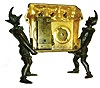 Mayer, Germany, 30 hour novelty clock, the gilt basket form case containing three panting dogs, their tongues moving in and out as the clock runs, the basket supported by flanking patinated harlequins, case front with Roman numeral white enamel dial and round thermometer scale, now with mounted thermometer, tall, rectangular 30 hour time only, movement with counterpoised pallet arbor and attachment for dog tongues, signed Mayer, c1870