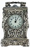 France, miniature carriage timepiece, the ornate silvered case with caryatid corners, masks, symmetrical foliate ornament and dolphin form carrying handle, top with thick beveled glass for viewing the escapement, Arabic numeral white enamel dial, blued steel spade and poker hands, 8 day time only, movement with lever platform, c1880