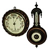 Barometers- 2 (Two) aneroid in carved walnut hanging cases; one signed Sidric, the other "F Rachmuhl Sohn, Basel."