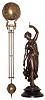 Ansonia Clock Co., New York, "Huntress Ball Swing", the patinated spelter figure of a young woman carrying game birds and holding the clock aloft in her left hand, mounted to an japanned cast iron base, 8 day time only, movement mounted inside a brass sphere with cast ribbon ornament and applied Arabic numerals, Louis XV style hands, the lower section in gridiron style with smaller sphere at the bottom, c1900