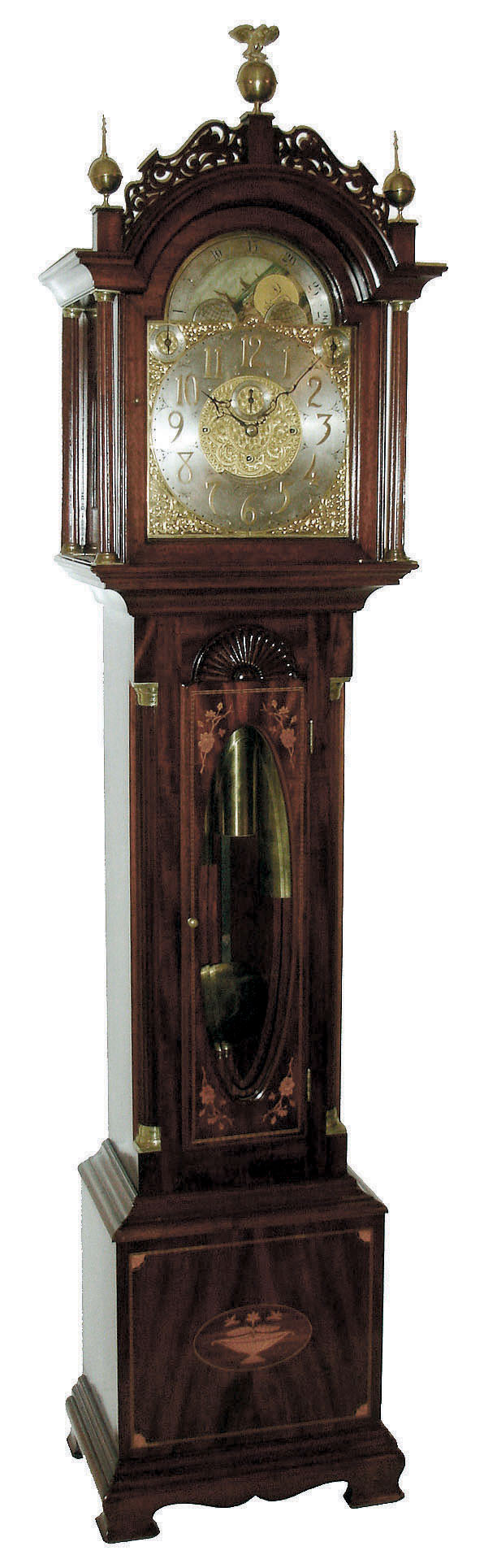 John Elliott, London, England for Bigelow, Kennard & Co., Boston, Mass., tall clock, time, strike and Westminster chime on cathedral gongs, 8 days, three brass, weight driven movement in a mahogany inlaid case with floral motif on door and urn with flowers on base, both framed with herring bone inlay, Roxbury fretwork and brass capped full Corinthian columns on hood, three upper brass finials including center eagle finial, trunk door surmounted by clamshell carving and flanked by fluted quarter columns with brass caps and bases, all resting on a cutout skirt with ogee bracket feet. The brass dial has ornately cutout and engraved brass corner spandrels and profusely engraved dial center silvered chapter ring with applied brass numerals, hour strike / silent and Westminster chime / silent selectors and moon phase dial, c1910 — Antique Clocks Price Guide