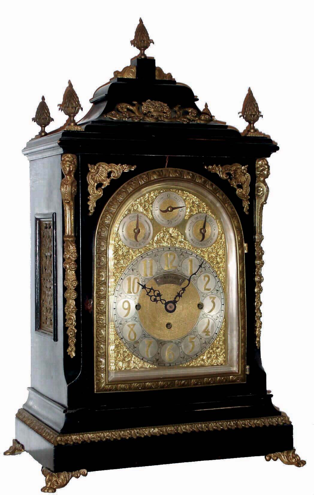 English, triple fusee, quarter chiming bracket clock, in a classic Georgian style large ebonized case with brass caryatids, side frets and pineapple finials, the whole resting on cast ÒtoedÓ feet, chiming your choice of Whittington on 8 bells or Westminster on 4 large flat wire gongs, and then sounding the hours on a still larger steel flat wire gong, the clock retailed by O. A. Strapp, Cambridge, and with an engraved cartouche below 12 bearing that information, and the arched dial with small subsidiary dials labeled Chime /Silent, F/S, and Chime on 8 Bells or Westminster, c1875 — Antique Clocks Price Guide