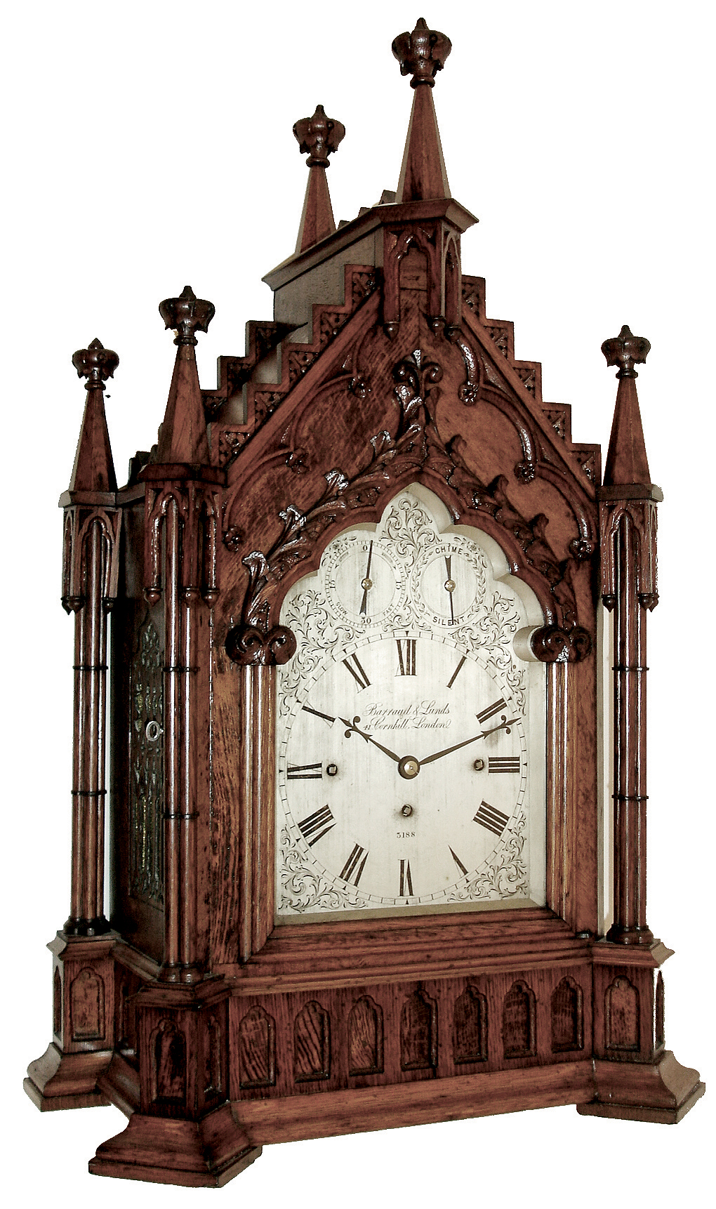 Barraud & Lunds, 41 Cornhill, London, large bracket clock in the Gothic style, carved oak case with buttress corners supporting clustered columns, the door also with clustered column style ornament and topped with foliate carving, gables with carved, stepped ornament, case top surmounted by 6 octagonal pinnacles with crockets, case sides with ornately pierced wooden frets, Roman numeral silvered dial with engraved spandrels, blued steel hands, 8 days, 3 train fusee movement, with chiming on eight bells and counting the hours on a large gong, the back plate also signed , c1845 — Antique Clocks Price Guide