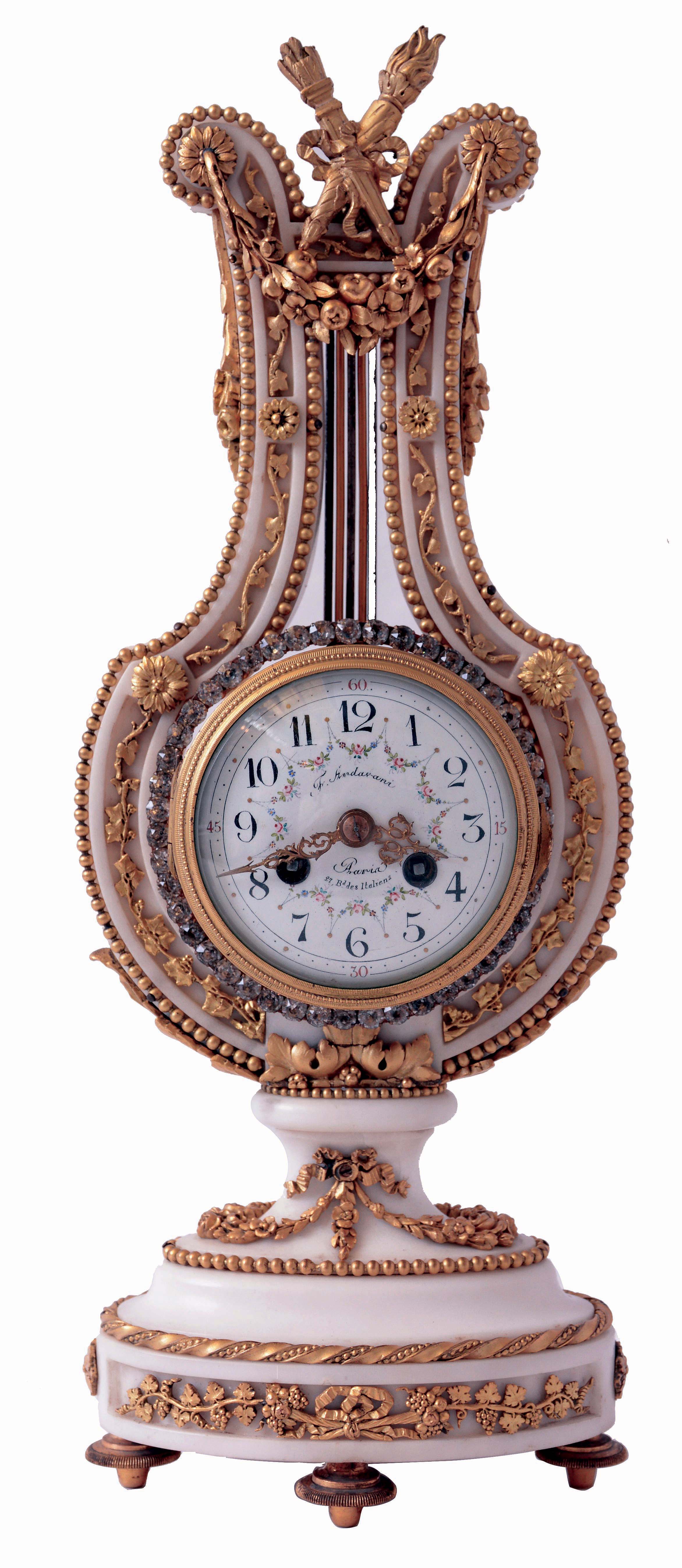 F. Ardavani, a Paris, lyre form mantel clock, white marble case with gilt bronze mounts, including fruit and floral festoons, trailing vines and other foliate ornament, the top with bowknot, torch and quiver, knife edge pendulum suspended behind the top ornament and with oscillating ring of brilliants, Arabic numeral white enamel dial with polychrome enamel garlands, 8 days, time and strike, pendule a Paris movement, c1900 — Antique Clocks Price Guide