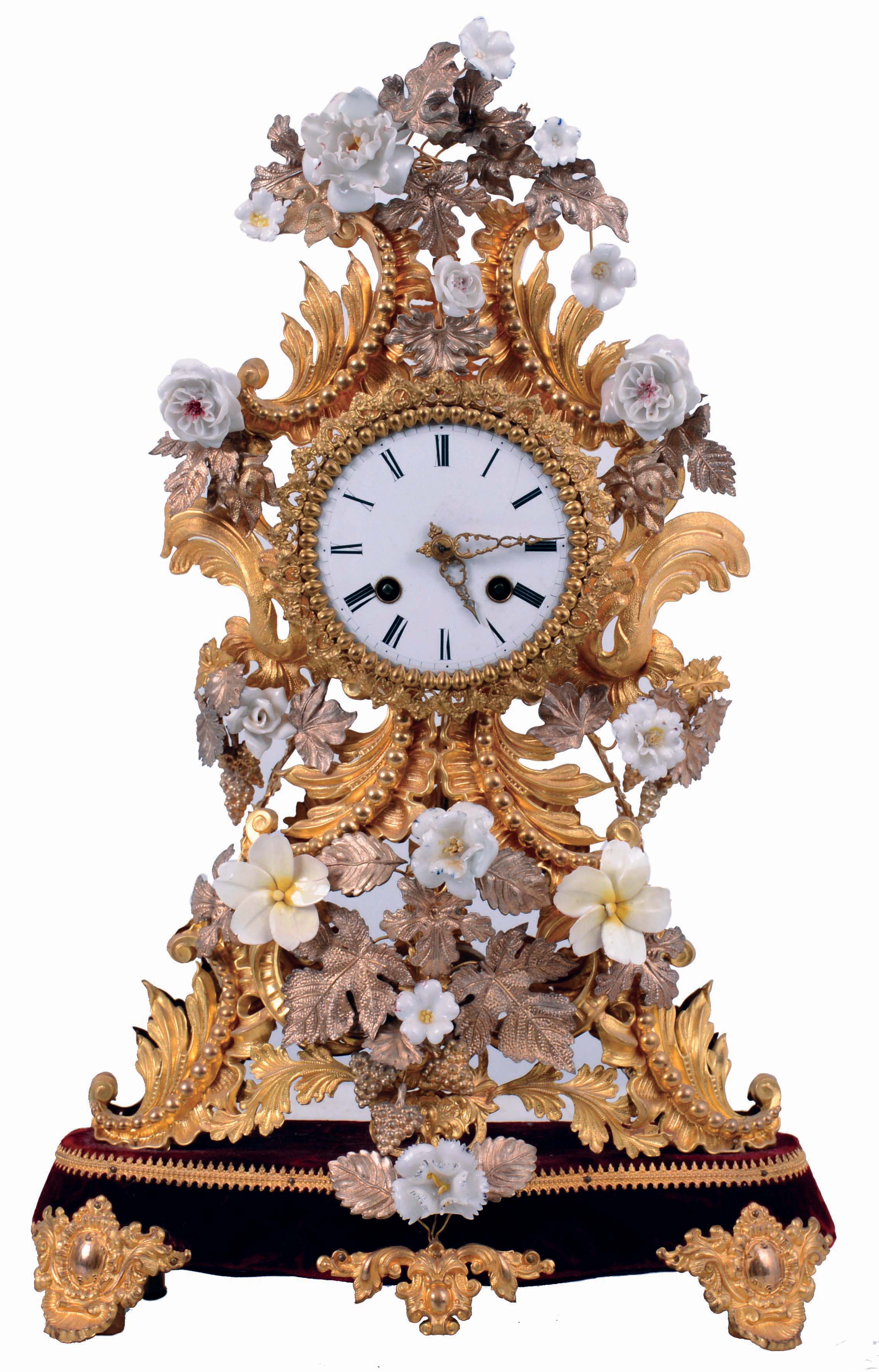 France, decorative mantel clock, the case of gilded and silvered stamped brass foliate elements in the rococo style, and with porcelain flowers, Roman numeral white enamel dial, fancy gilt hands, 8 days pendule a Paris movement with silk thread suspension, striking on a bell, the back plate marked "B & C Paris", mounted to a velvet covered wooden base with gilt feet and central ornament, c1850 — Antique Clocks Price Guide