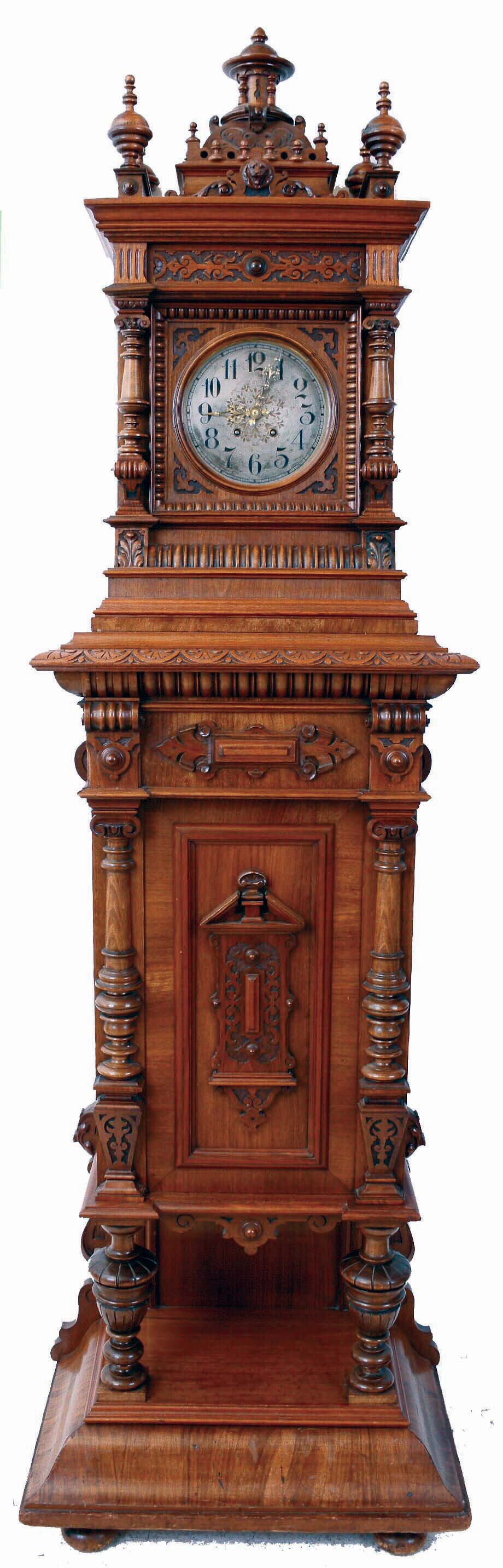 Lenzkirch, Germany, Symphonion Hall Clock, style No. 25 ST., walnut case with heavily molded base and standing on compressed ball feet, richly ornamented with veneers, turned elements and carving, mid section with door concealing the music player and disc, Arabic numeral silvered dial with fancy, piered brass hands, 14 day time and strike movement, which activates the music box following the hourly strike, serial #1148313, c1897 — Antique Clocks Price Guide