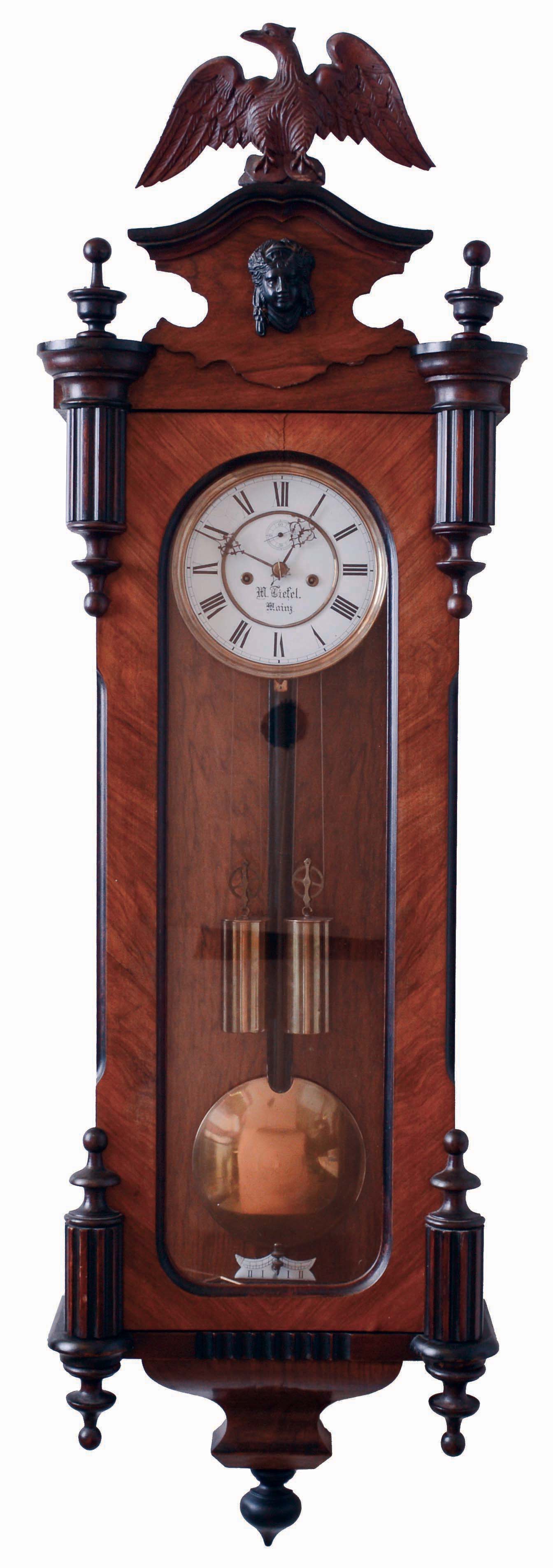 Lenzkirch, Germany 2-weight "Vienna Regulator" in a walnut veneer case with four half finials mounted toward the center of the door, and full finials top and bottom, and with original top trim and spread eagle, serial #650,560, This clock retailed by M. Tiefel, Mainz, Germany, as noted on dial, c1884. — Antique Clocks Price Guide