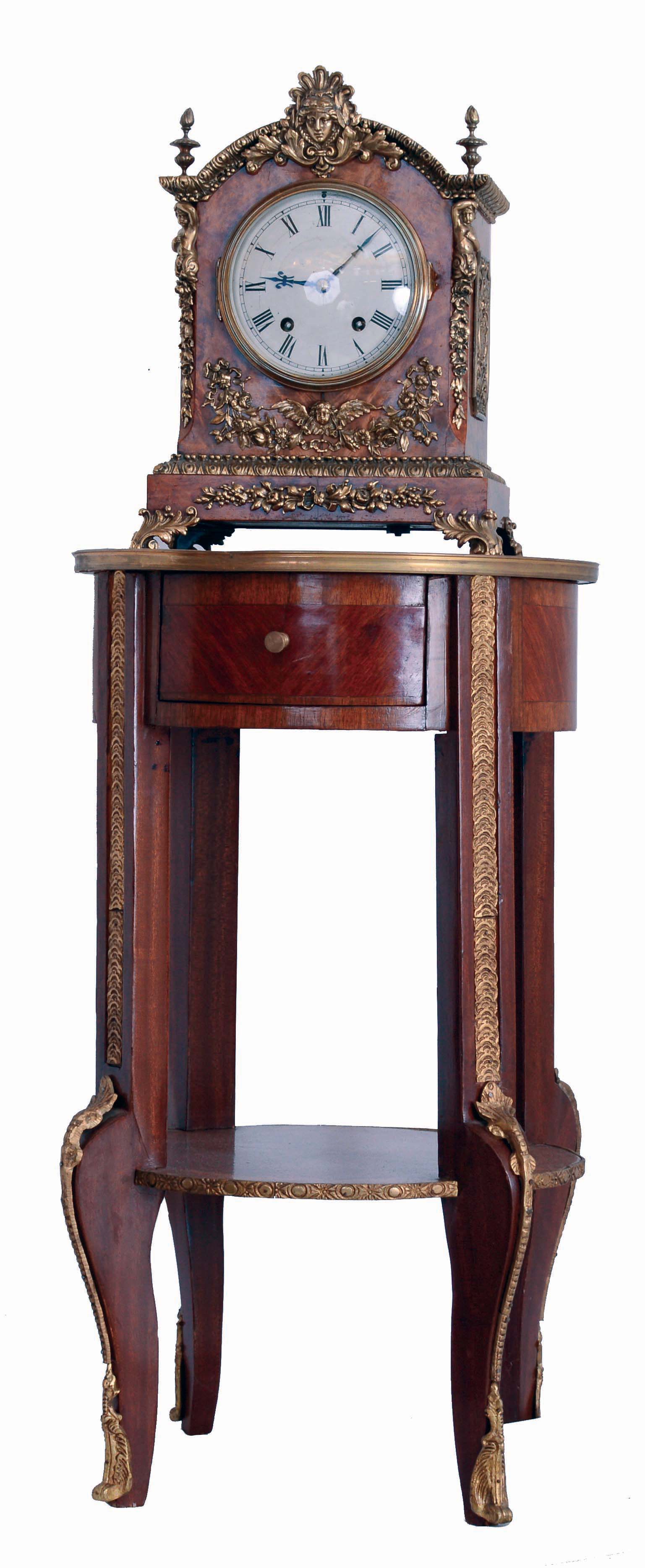 Lenzkirch, Germany, shelf clock of typical bracket clock form, mahogany and burled mahogany veneers with classically inspired applied ormolu castings and caryatid corners, gilt scroll feet, gilt flame finials, and medallion centered gilt frets. The silvered Roman dial ring has a regulating adjustment, blued steel hands, 8 days time and strike movement with ting tang striking, serial # One Million 9277, also marked "52", c1894 including period one drawer round mahogany stand with brass trim — Antique Clocks Price Guide