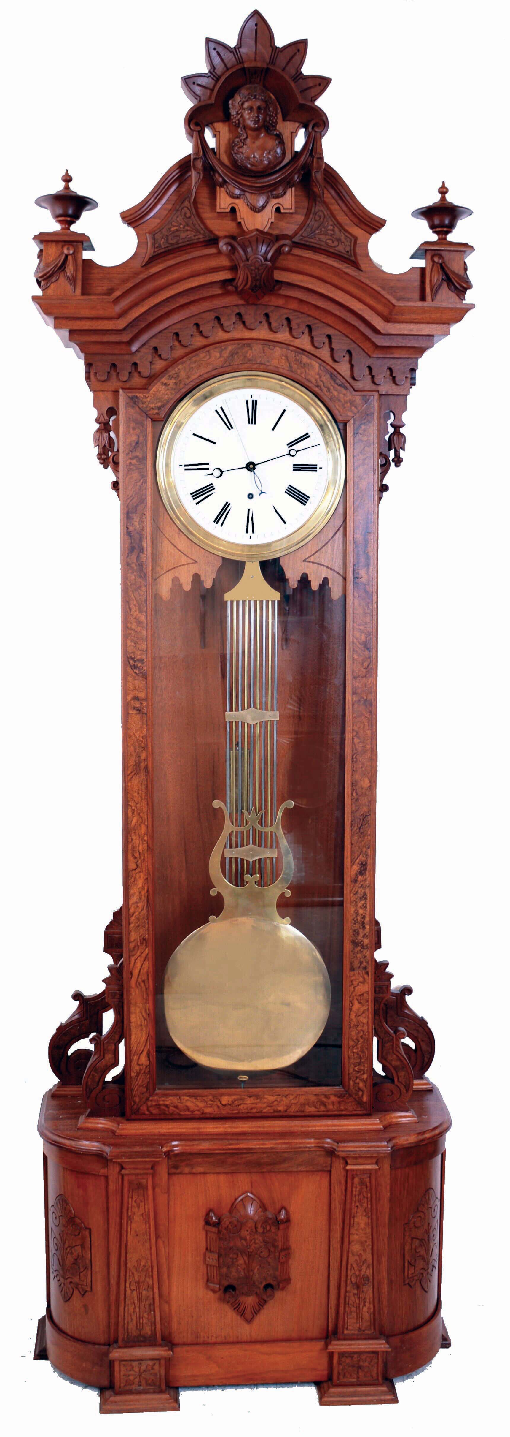 Wm. L. Gilbert Clock Co., Winsted, Conn., "Regulator No. 7", floor standing jeweler's regulator, 8 days, time only, brass weight driven Swiss pinwheel movement with a white enameled dial, lyre gridiron pendulum in a walnut case with burled highlights and intricately carved crest with busty lady figure, c1881 — Antique Clocks Price Guide