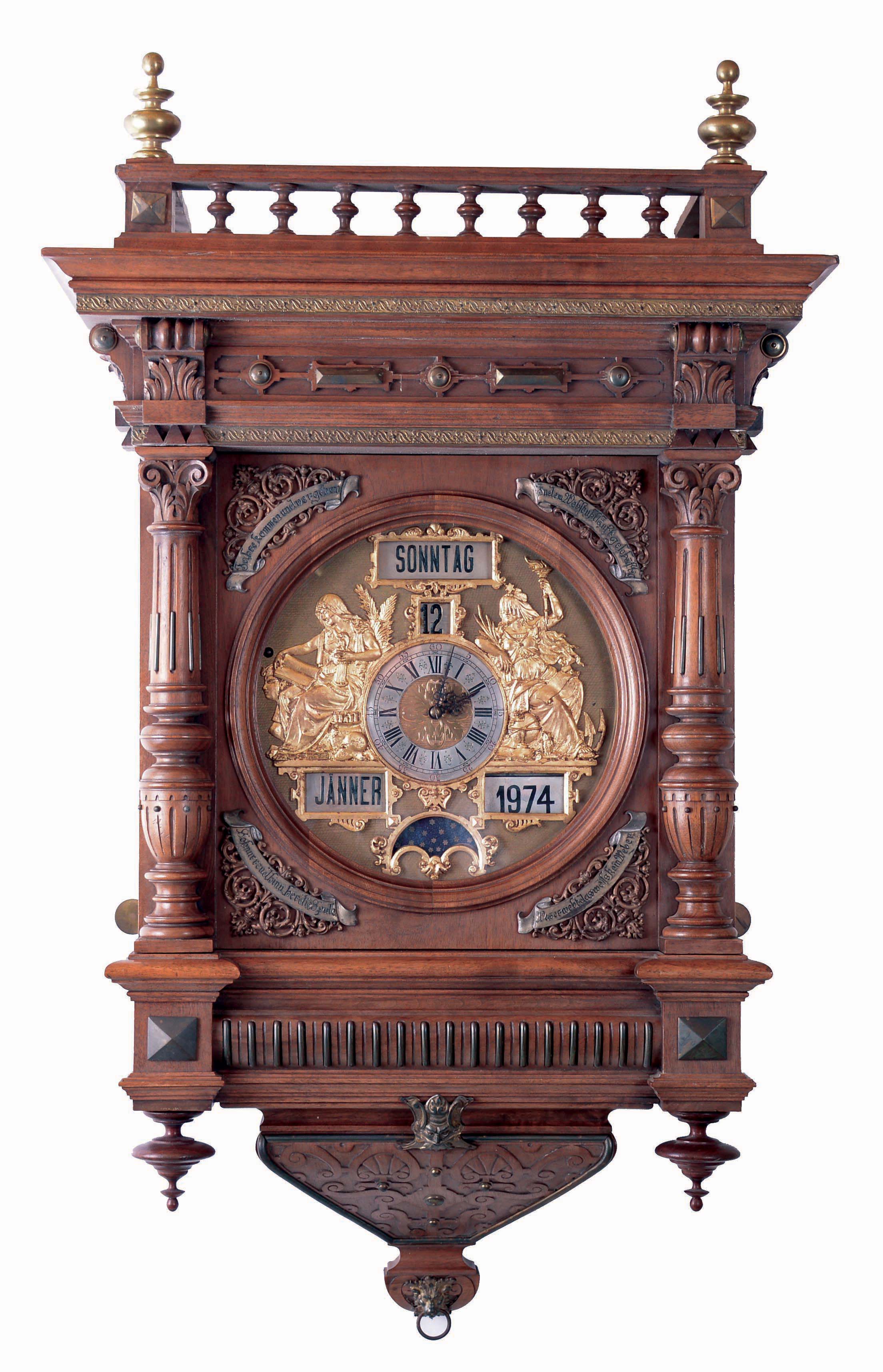 J. Salfer, Wien, large walnut wall clock, the case with turned and carved architectural elements, and with applied brass ornament, bottom with carved bracket, door with applied spandrels, each with a banner inscribed with a short phrase in German, top with balustrade and brass finials, matted brass dial with applied female figures flanking the silvered dial with Roman numeral chapter, and calendar display apertures at 12:00, 5:00 and 7:00, fancy blued steel hands, massive, long running movement with day/ date/ month calendar, and with phases of the moon, with provision for starting the pendulum without opening the case, the main "I" shaped plate with auxiliary strike movement attached at upper left, c1870 — Antique Clocks Price Guide