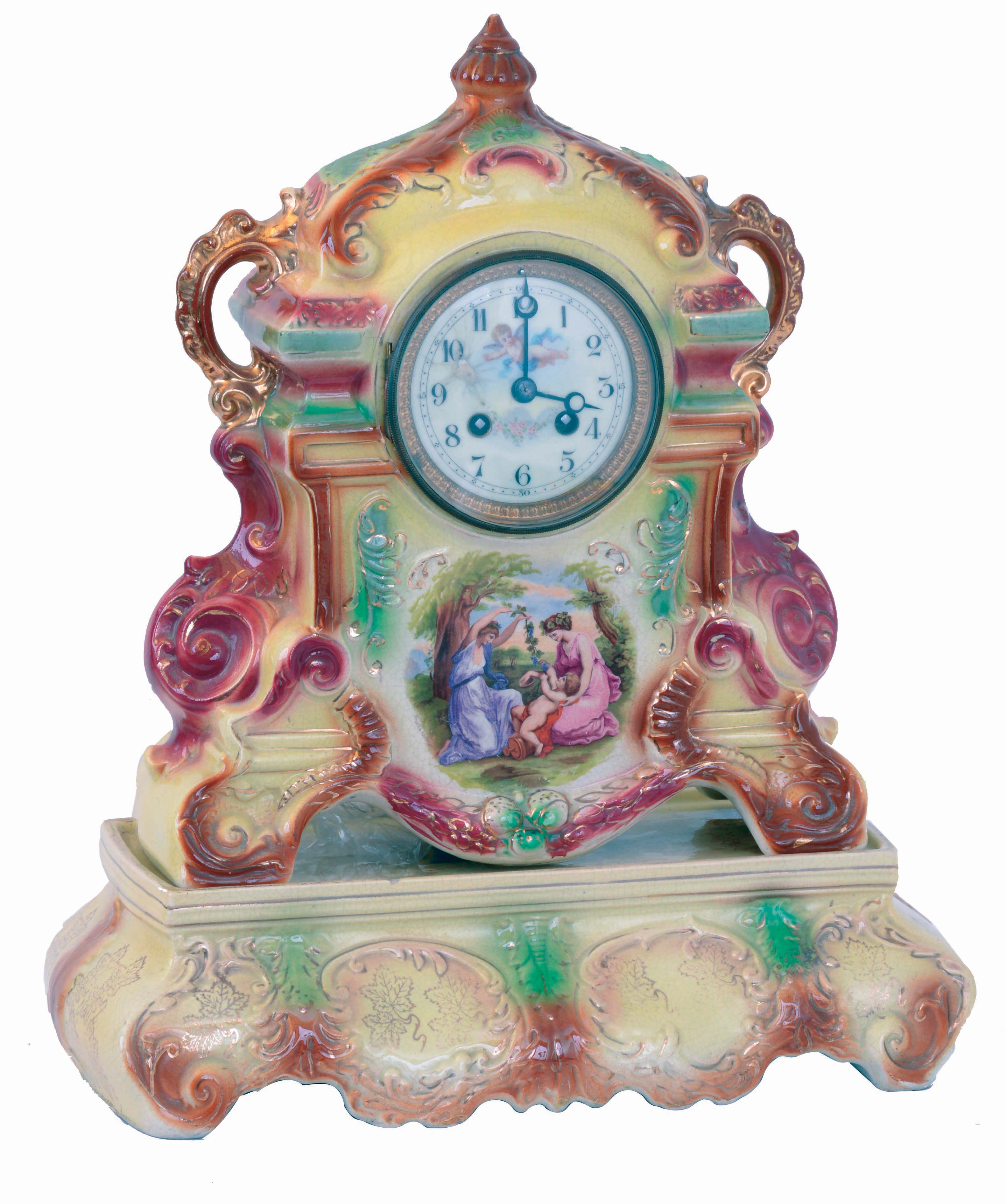 England, Strasburg Ware clock, with French movement, colorful earthenware case, enamel scene with figures in a landscape below the dial, Arabic numeral white enamel dial with putto and floral festoon, the case resting on its original Strasburg Ware base, 8 days, time and strike movement, c1920 — Antique Clocks Price Guide
