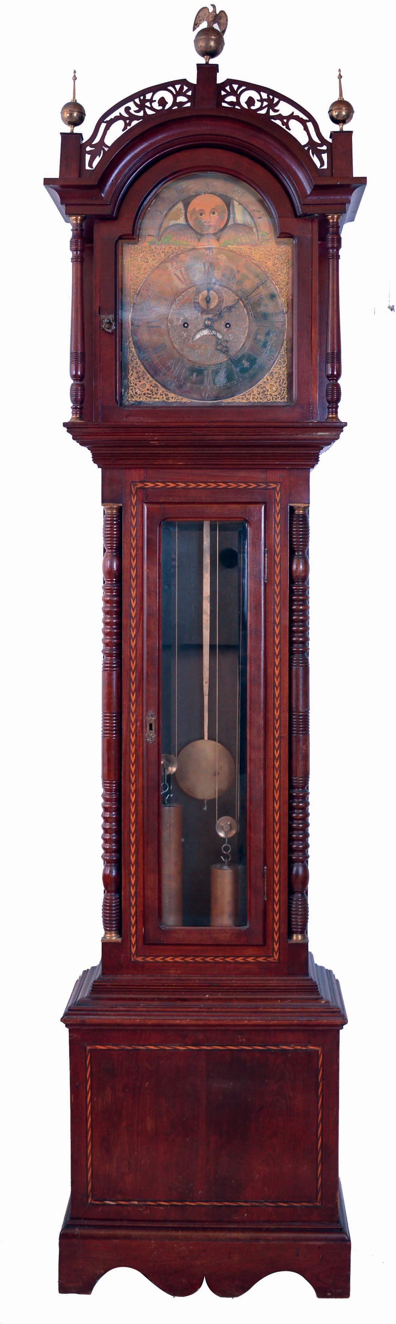 Ty Burtt, England, tall case clock, 8 days, time and gong strike, brass weight driven movement in an inlaid cherry case with with fret work hood, brass finials including eagle center, full turned columns flanking hood, beveled glass trunk door flanked by full columns and applied bracket base. The brass dial has silvered chapter ring, applied brass numerals, moon phase and date calendar, c1895 — Antique Clocks Price Guide