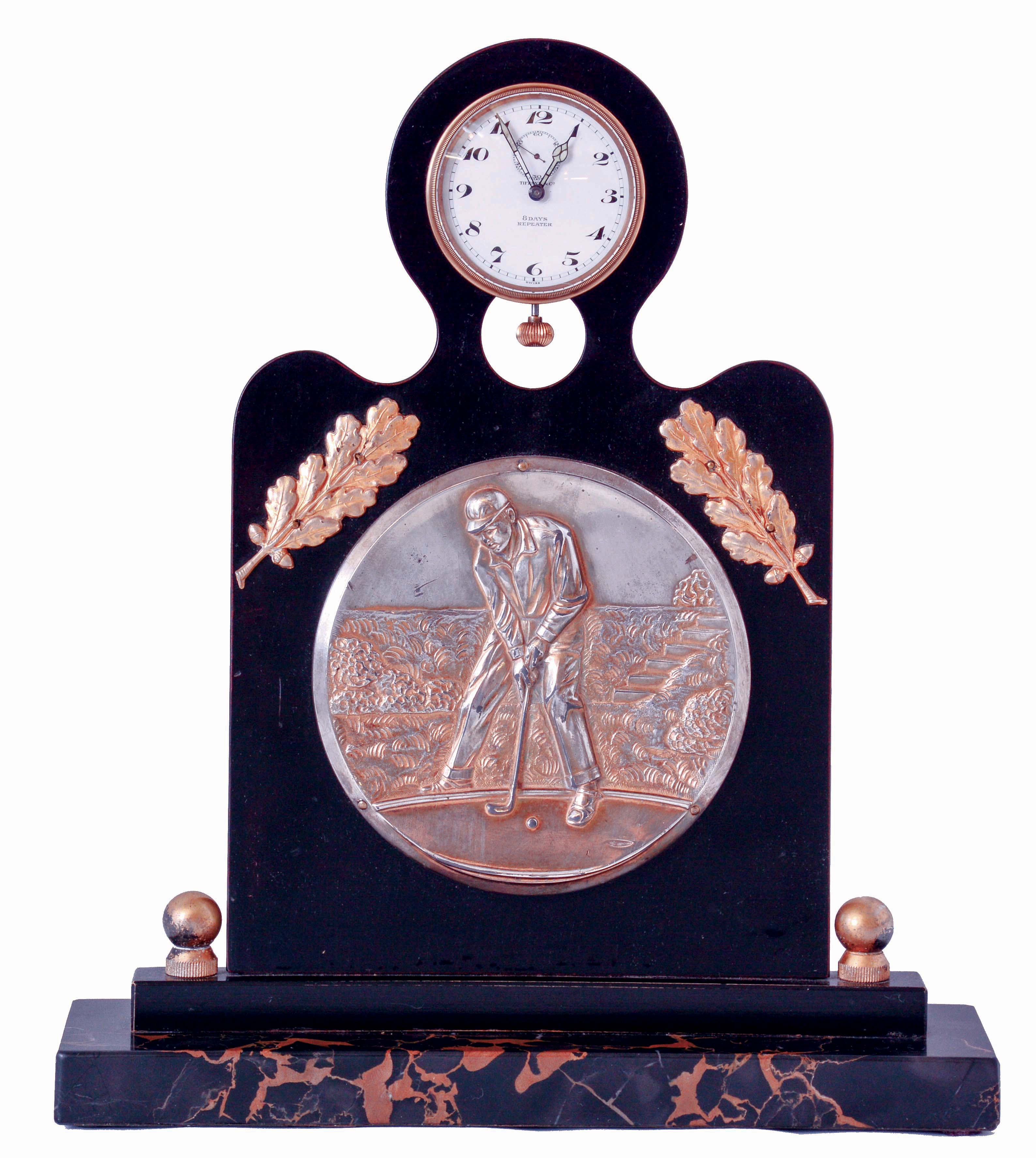 Angelus Watch Co., Switzerland, for Tiffany & Co., New York, golf themed desk clock, portoro marble base supporting an ebonized wood stand, mounted with a silver gilt repoussE plaque depicting a golfer putting, with two applied gilt branches with oak leaves above, and with clock mounted at the top, the 8 days, 15 jewel, minute repeating nickel plate movement with centrifugal governor, lever escapement, and cut bimetallic balance, Arabic numeral white enamel dial, signed "Tiffany & Co., 8 Days Repeater", with blued steel luminous hands, case back dated May 14, 1932 — Antique Clocks Price Guide