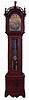 Ty Burtt, England, tall case clock, 8 days, time and gong strike, brass weight driven movement in an inlaid cherry case with with fret work hood, brass finials including eagle center, full turned columns flanking hood, beveled glass trunk door flanked by full columns and applied bracket base. The brass dial has silvered chapter ring, applied brass numerals, moon phase and date calendar, c1895