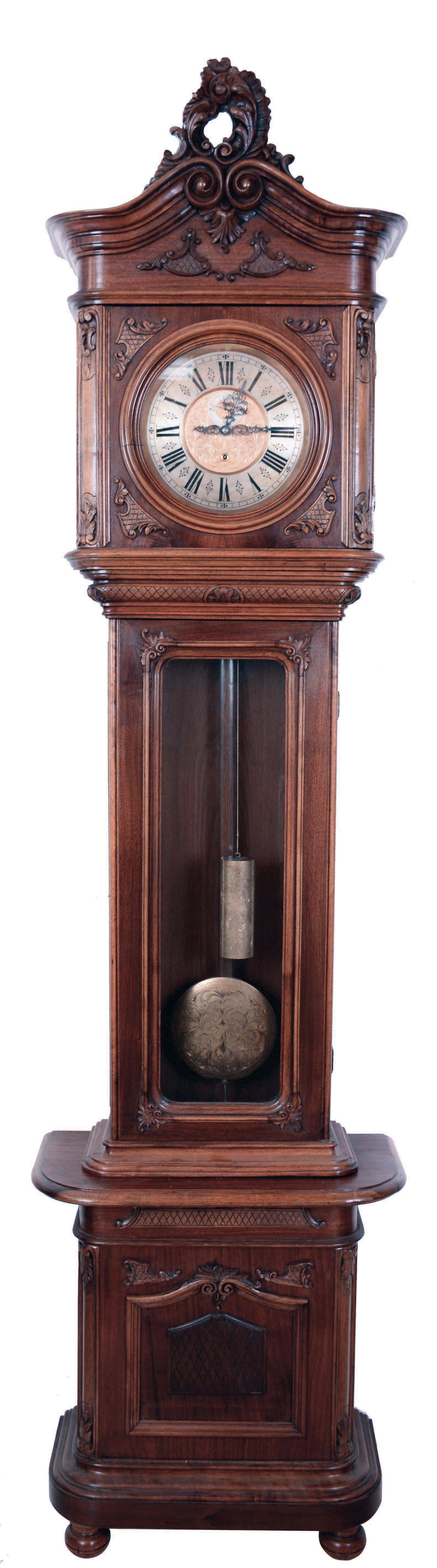 Austrian tall clock, long duration 30 days, time only, single brass weight driven movement in a carved walnut 2nd Baroque style case with bun feet, a checkered panel in base plinth and below hood, simulated broken arch with a very fancy carved pediment and glazed sides of hood and trunk. The brass dial with silvered chapter ring and engraved center has second's bit and fancy metal hands, c1890 — Antique Clocks Price Guide