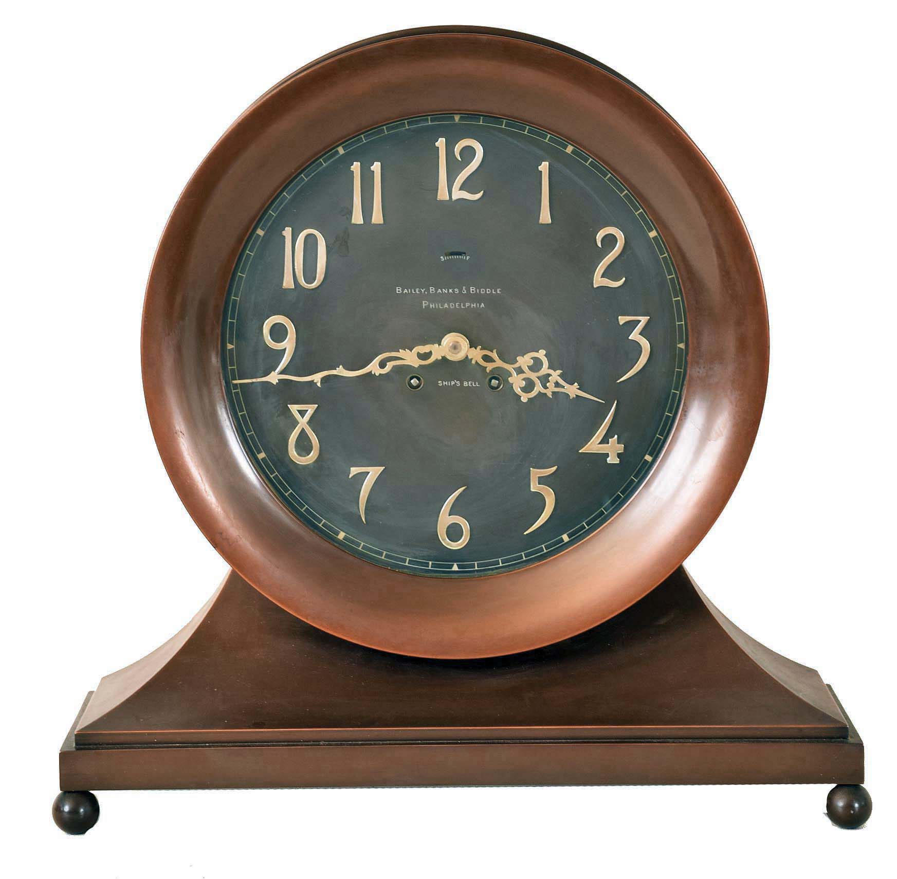 Chelsea Clock Co., Boston, Mass., "Copper Bronze Constitution Ship's Bell Clock" for Bailey, Banks & Biddle, Philadelphia, 8 days, time and ship's bell strike, spring driven movement in a bronze finished brass case on ball feet with large 10" dial with applied silvered numerals and finely wrought hands, serial #34533 — Antique Clocks Price Guide