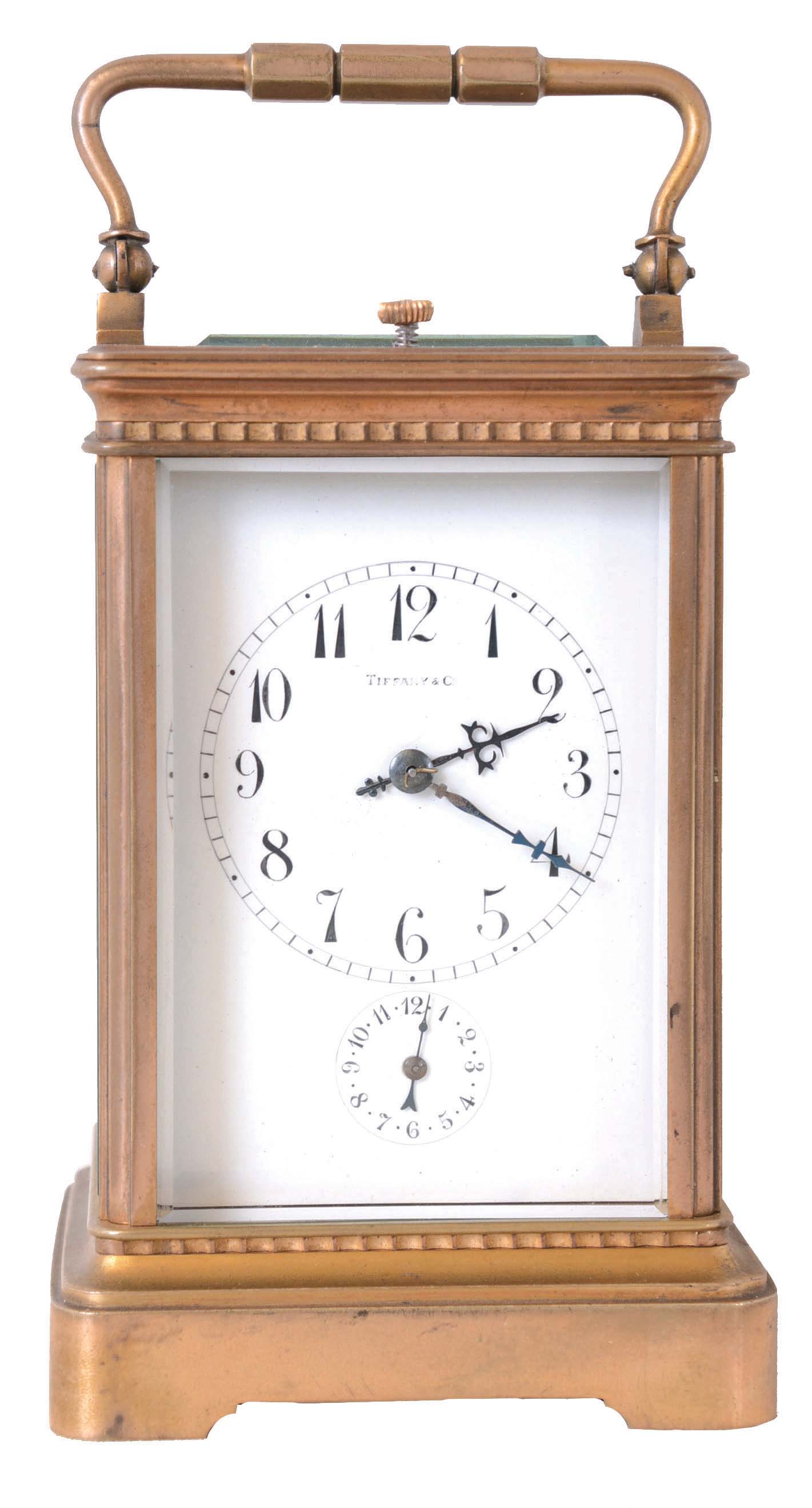 France, for Tiffany & Co., grand sonnerie striking carriage clock with alarm, gilt Corniche variant case with beveled glasses, Arabic numeral white enamel dial with subsidiary alarm chapter, blued steel hands, 8 day quarter striking movement with lever platform, striking the hours and quarters in passing, and repeating on demand — Antique Clocks Price Guide