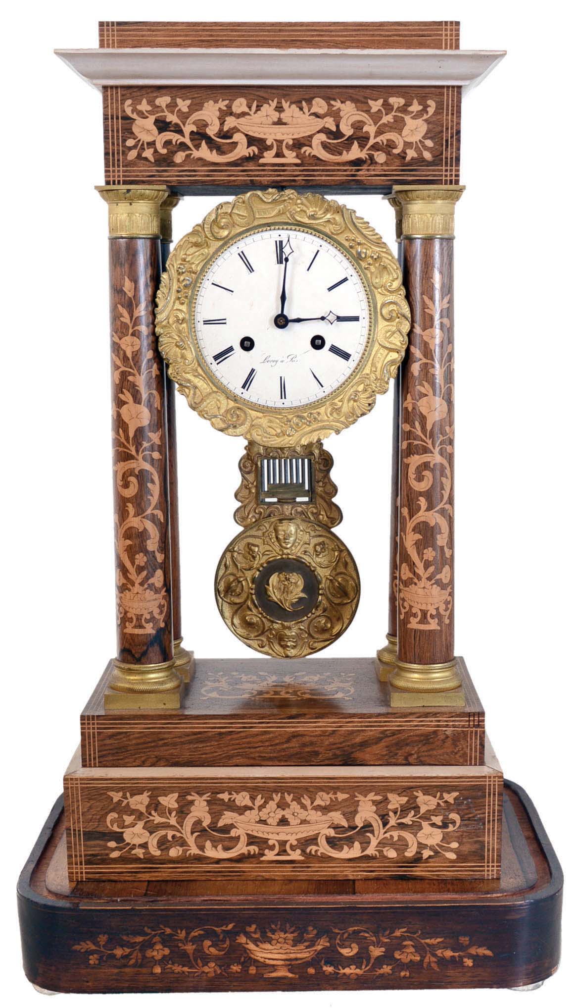 France, portico clock, rosewood veneered case with contrasting stringing and floral inlays, columns with gilt capitals and bases, top and base with ogee molding, gilt bezel and grid iron pendulum with serpents and scroll design, Roman numeral white enamel dial, steel blue hands, 8 days, time and strike movement marked LeRoy a Paris all resting on a rosewood veneered base — Antique Clocks Price Guide
