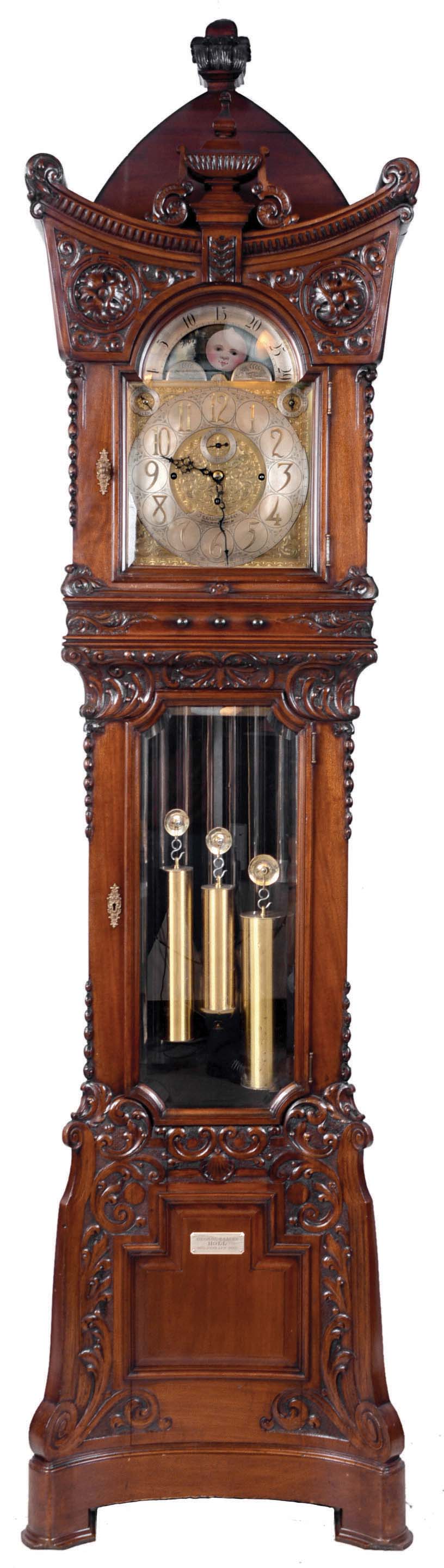Walter H. Durfee, Providence, Rhode Island, for J.E. Caldwell & Co., Philadelphia, Penn. on dial, 8 tube hall clock, 8 days, time, strike and quarter chimes. three weight driven, damascened movement. Plays Westminster or tunes on "Bow Bells". Tubes signed by Walter Durfee with patent dates 1892 & 1896. The case is carved mahogany with an ornately carved pagoda shaped hood with carved urn finial above dial, bent pyramid top surmounted by a square carved finial at apex. The trunk and hood doors have matching brass escutcheons and beveled glass. The carved curve base resting on bracket feet has a retailer panel with presentation plaque to "GEORGE & LAURA HOLL 1873. JUNE 25TH. 1895". The brass dial has moon phase, engraved spandrels and dial center, silvered chapter ring, strike / silent and tune selector discs. [Note: George Holl, Jr. (1840-1915) and Laura Stockton (1851-1920) were married June 25, 1873 at Camden, NJ and lived the rest of their life there. This clock was a 22nd. anniversary gift.] — Antique Clocks Price Guide