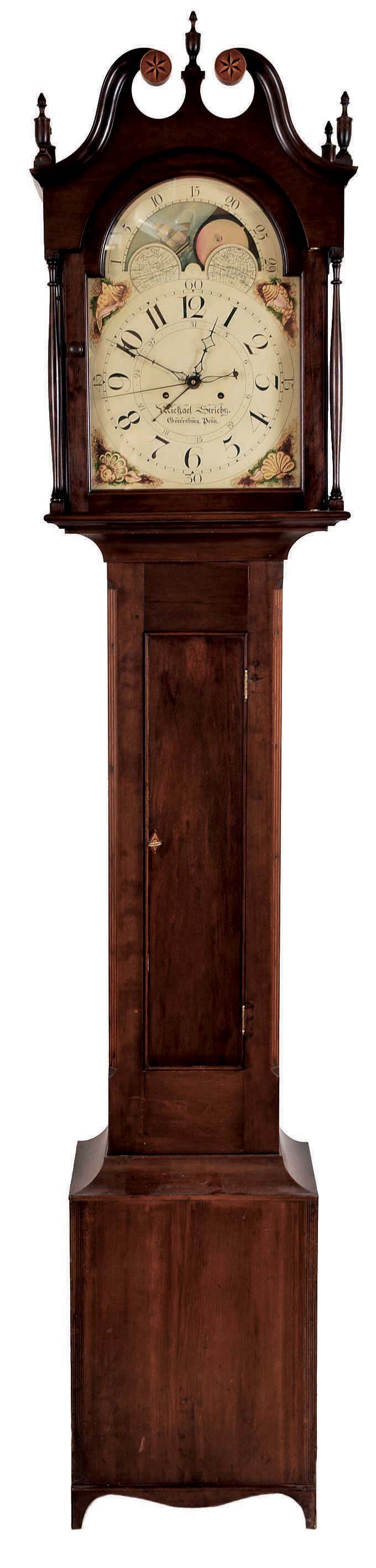 Michael Strieby, Greersburg, Penn., tall case clock, with significant restoration. 8 day, time and strike, weight driven movement in a cherry case with broken arch top, five turned wood finials, star inlaid rosettes and four full columns flanking hood, string inlaid cut corner columns, reeded accents on base and cutout Hepplewhite bracket feet. The painted metal dial with maker's signature has date calendar, sweep seconds and moon phase. — Antique Clocks Price Guide